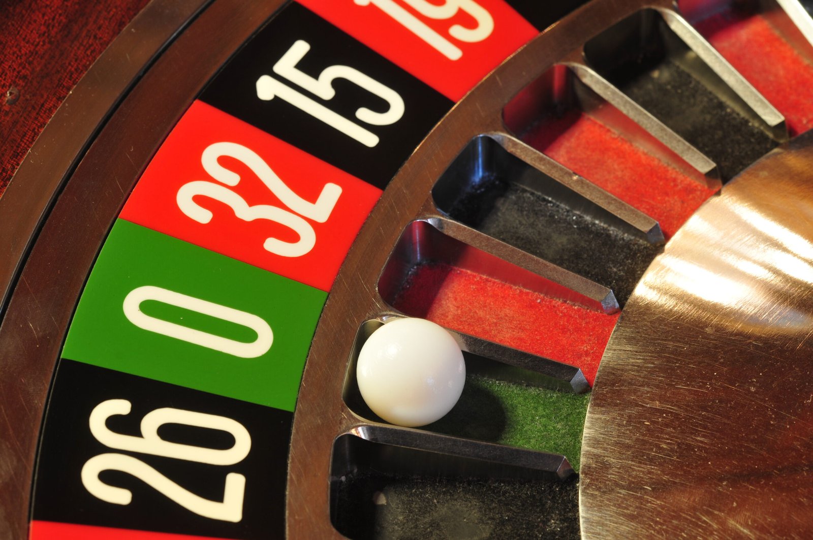 Close-up of a European roulette wheel with the ivory ball resting near the green zero pocket